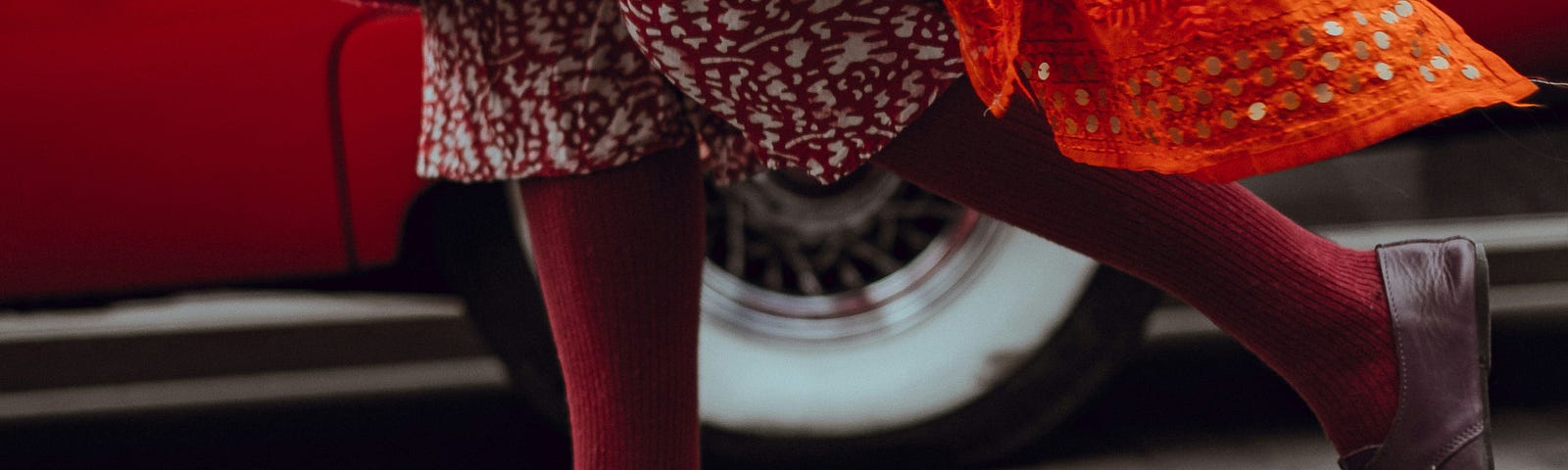 View of well dressed, lower limbs of a lady in purple stockings, black lace-ups, red coat and colorful print dress. If you’re going to make a point, you gotta get their attention.