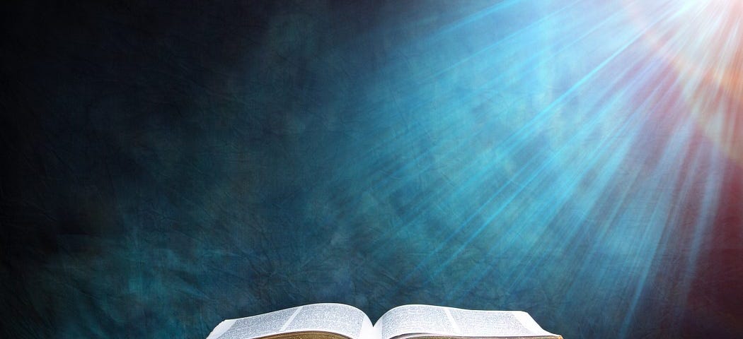 A picture of an open Bible on a desk, with a beam of light shining down on it