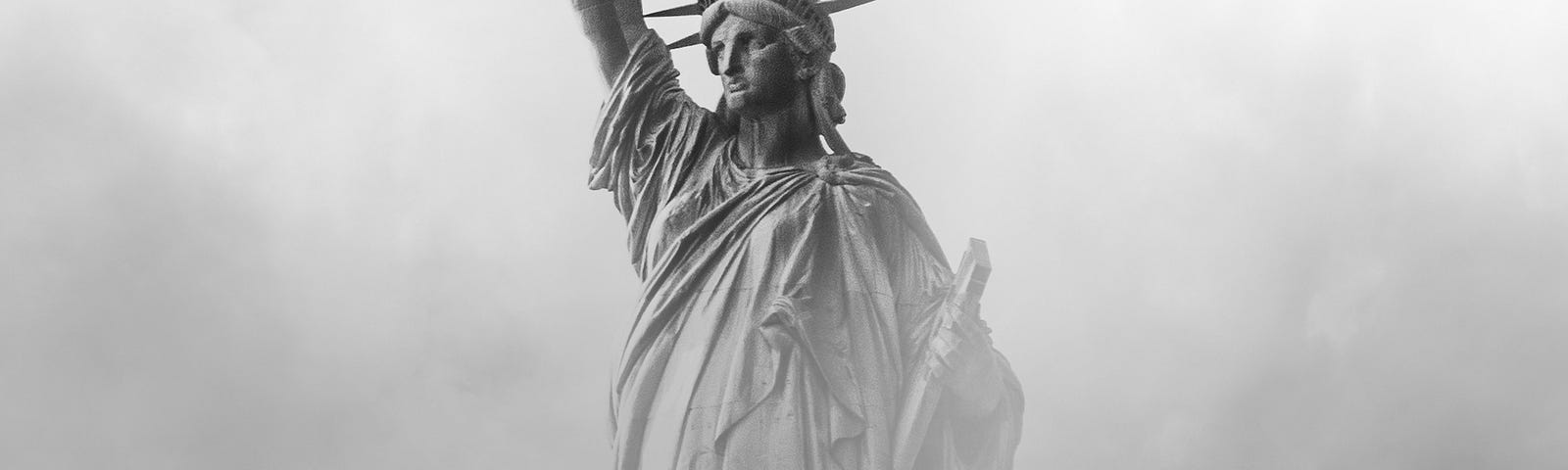 The Statue of Liberty waist up out of a mist. All in grays, black and white.
