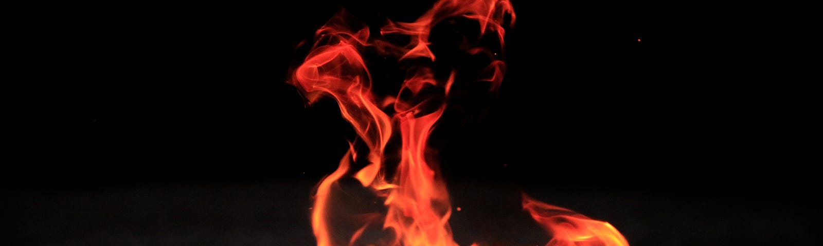 Photo of bright orange, red and yellow-white flames against a black background.