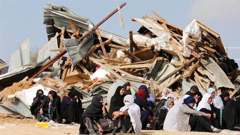 Mujeres beduinas sentadas junto a las ruinas de sus viviendas demolidas por excavadoras israelíes en Um al Hiran. (Foto: Amar Awad / Reuters)