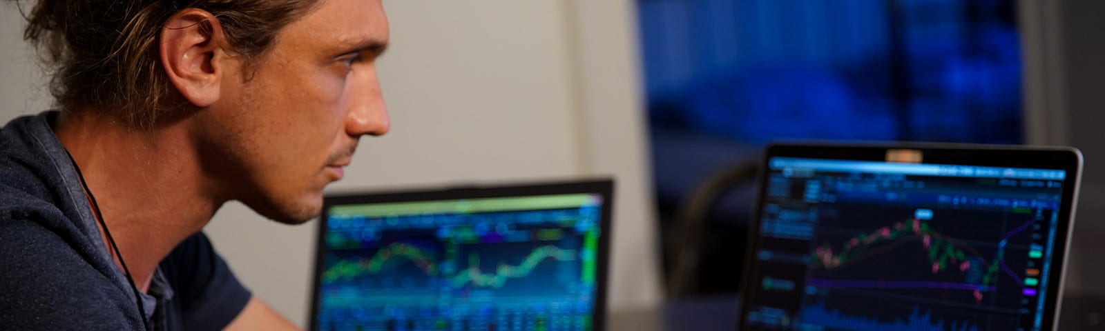 Man sitting at a computer screen looking at trading charts.
