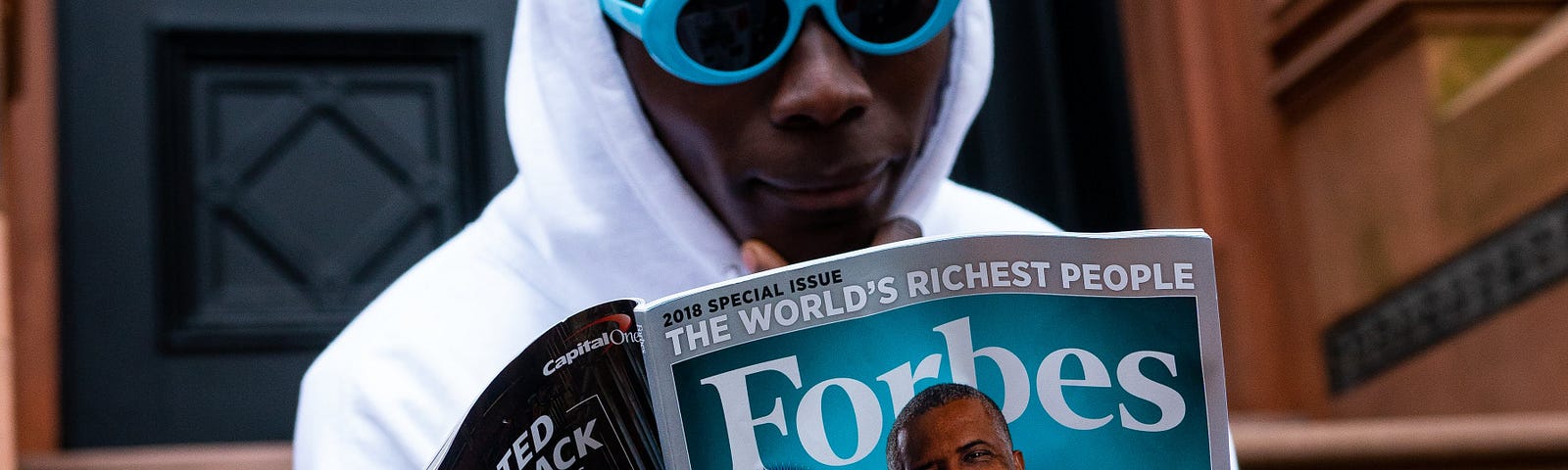 A man reading Forbes magazine with Billionaires on the cover