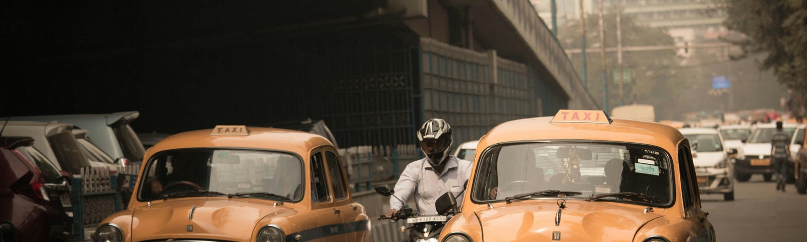 Two yellow cars on roads of India surrounded by traffic. Photo by Hitesh Choudhary on Unsplash.