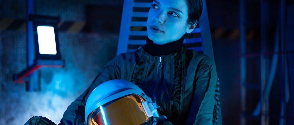 Woman In A Spacesuit Holding A Helmet and Looking Thoughtful