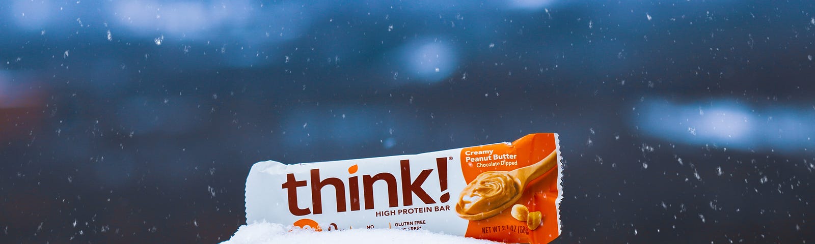 A “think” brand protein bar sits on a snow-covered rock. Protein bars are convenient and portable. On occasion, they can be a meal replacement option. But is your protein bar healthy? The quick answer is that it depends. The ingredients, protein amount, and overall nutritional profile matter greatly.