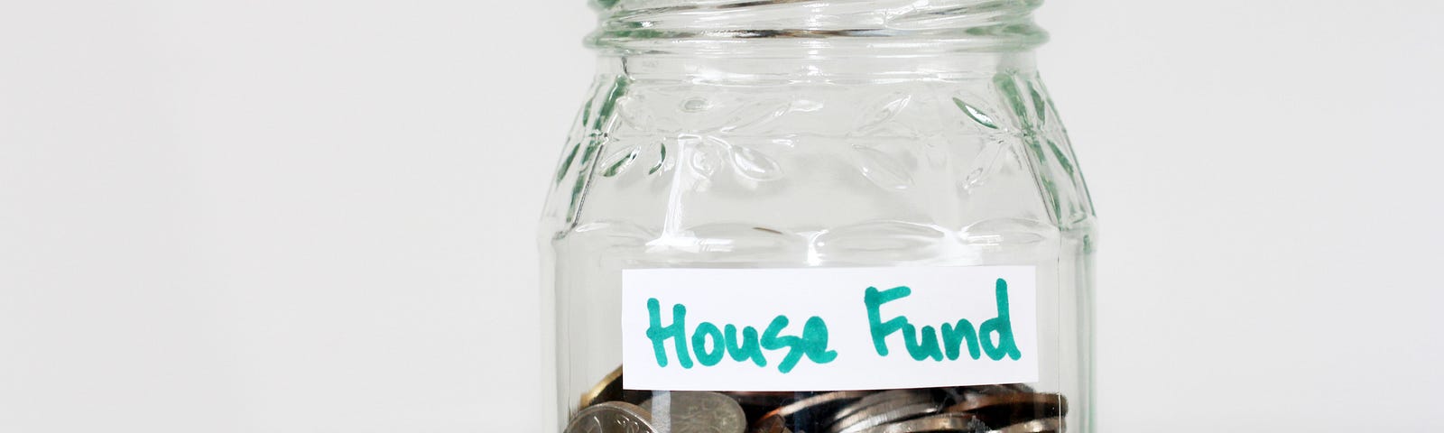 Glass jar with coins labelled “house fund”