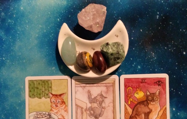 3 Cat Tarot cards with crystals on a starry blue background