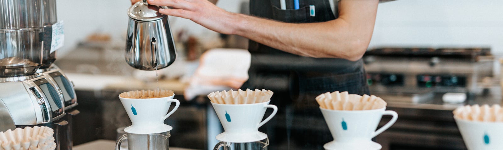 A barista sets up for multiple pour-over coffees to serve to their customers.