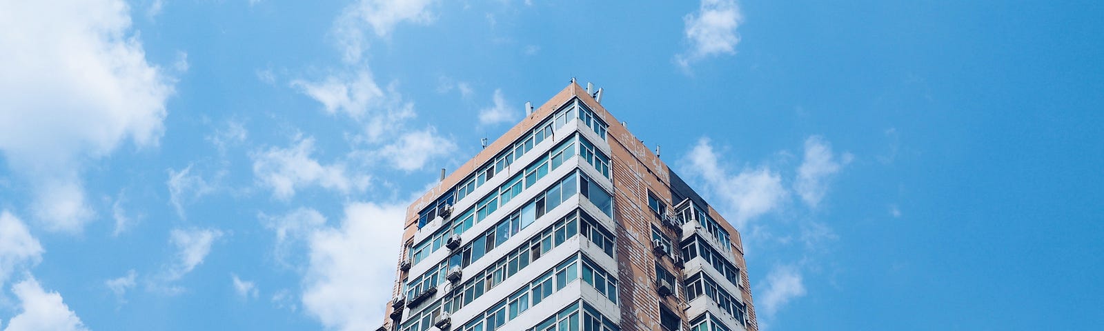 The top of an apartment building, against the background of a clear sky with a few clouds.