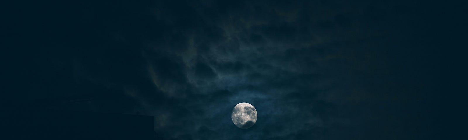 full moon partially behind clouds