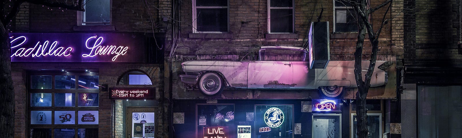 Picture of night scene: a bar at night — with a pink cadillac up top and dark city sidewalk area