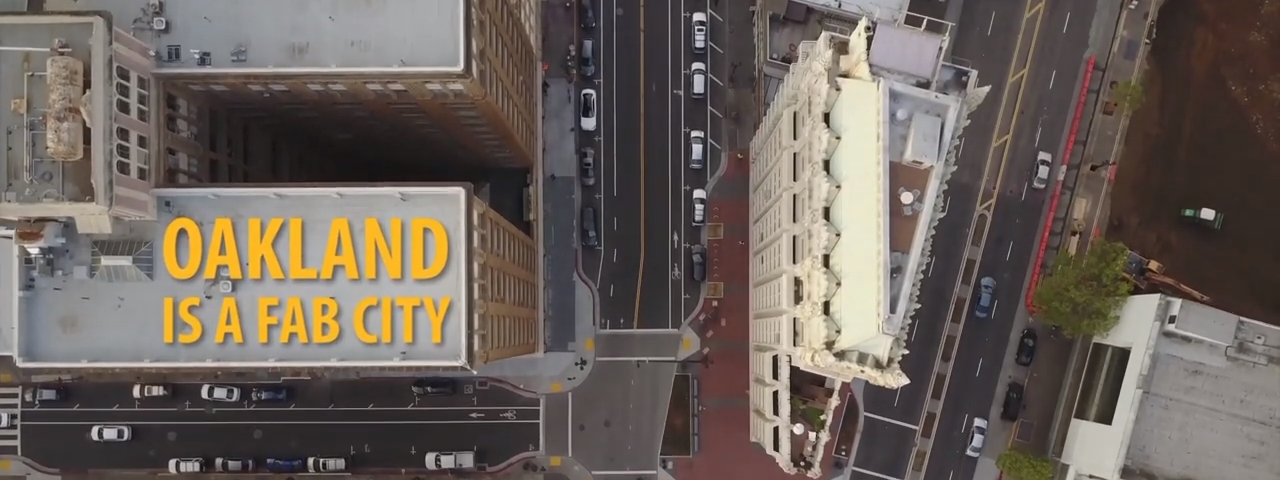 A bird’s eye view of Oakland with the words “Oakland is a Fab City” overlaid on one of the building’s rooftops.
