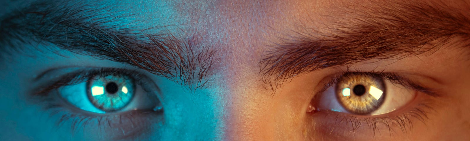 A picture showing a man’s eyes and the surrounding area of the face. One side is coloured in a cold blue, including the left eye’s iris. The other side is coloured in a warm orange.