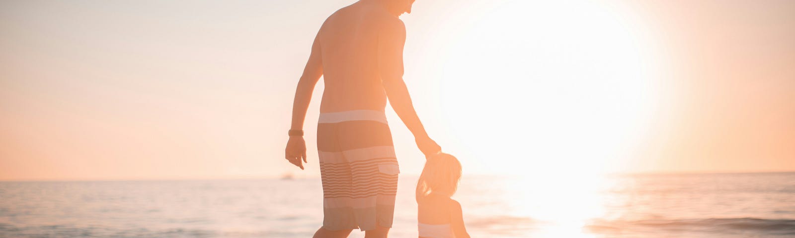 man walks with child on beach