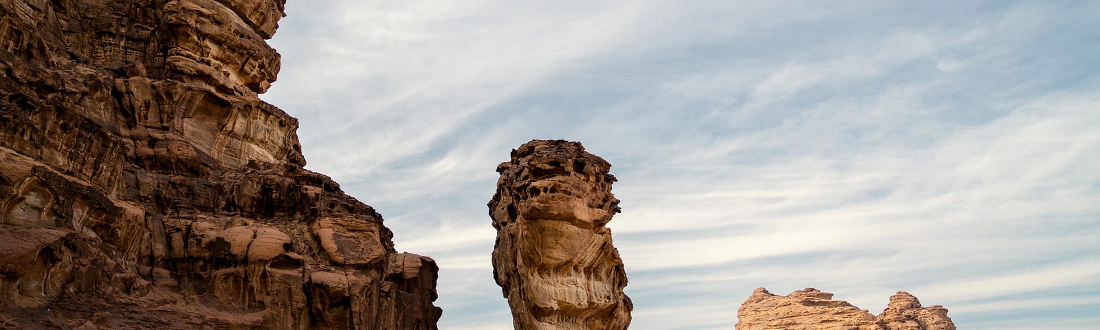 a person standing near a natural monolith in a desert landscape