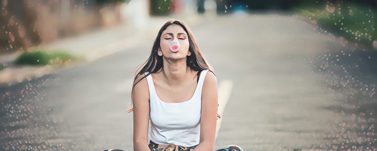 Girl sitting in the middle of a street chewing bubble gum
