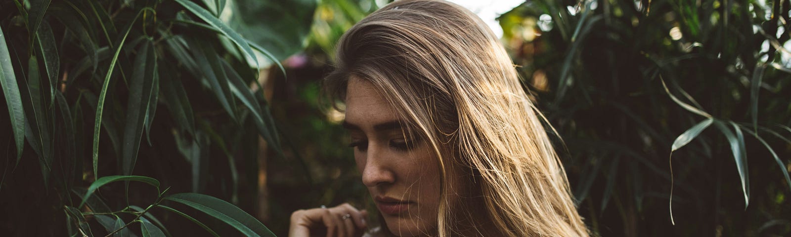 Photo of a woman surrounded by trees and bushes looking verydistressed.