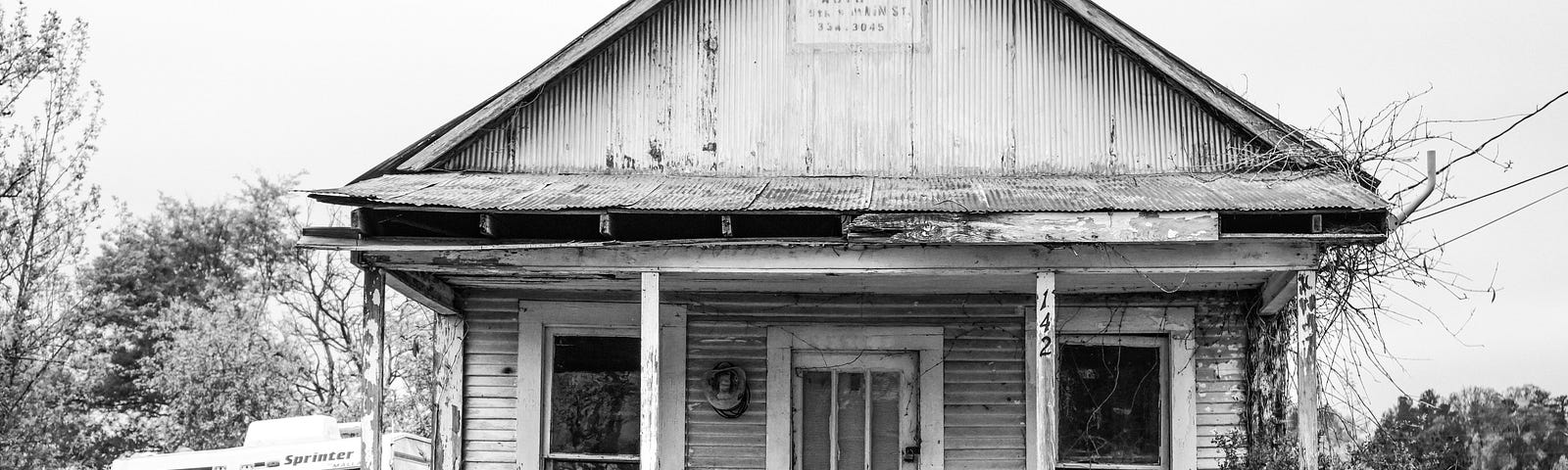 Old abandoned home black and with parked RV.