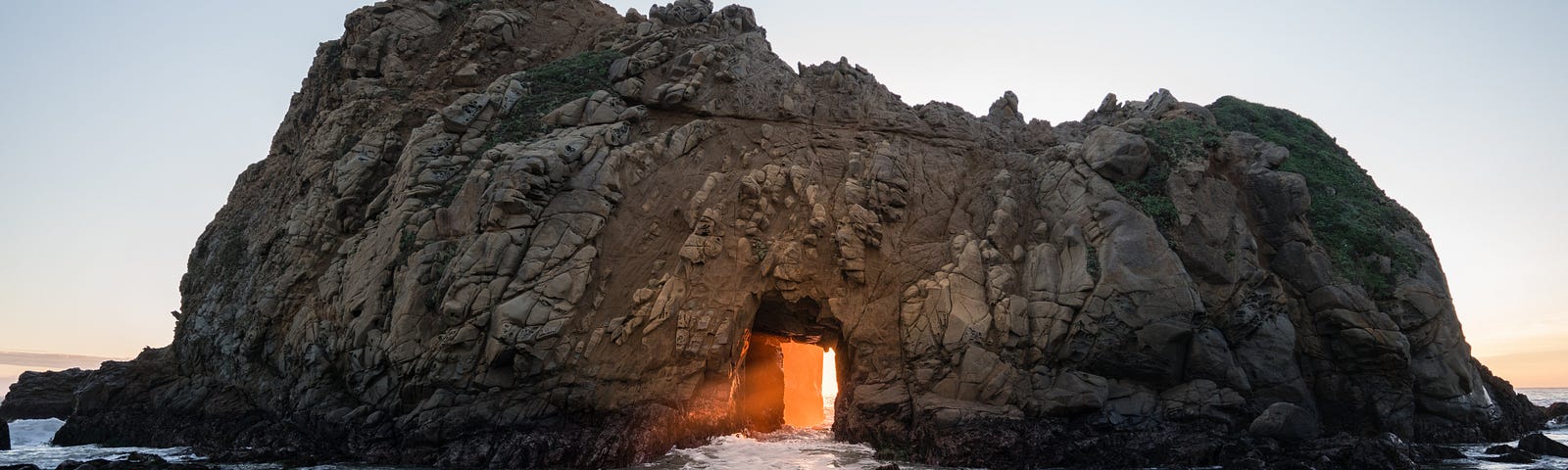In the sea, the pierced rock lets the rising sun pass through