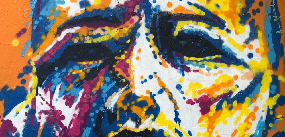 Blue/orange mural of a woman’s (?) face. Dot art.