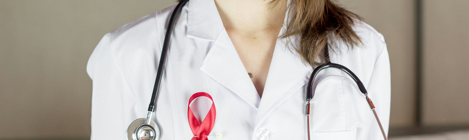 person in medical scrubs wearing a red ribbon pin for HIV/AIDS awareness