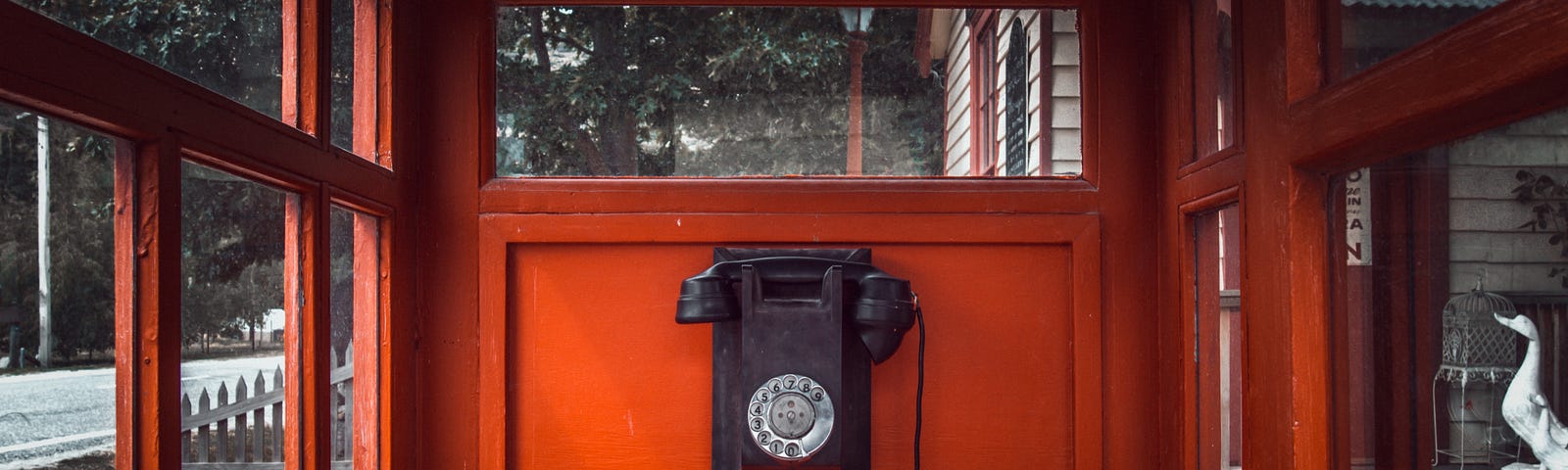 Antigue phone inside a large wooden phone booth with windows