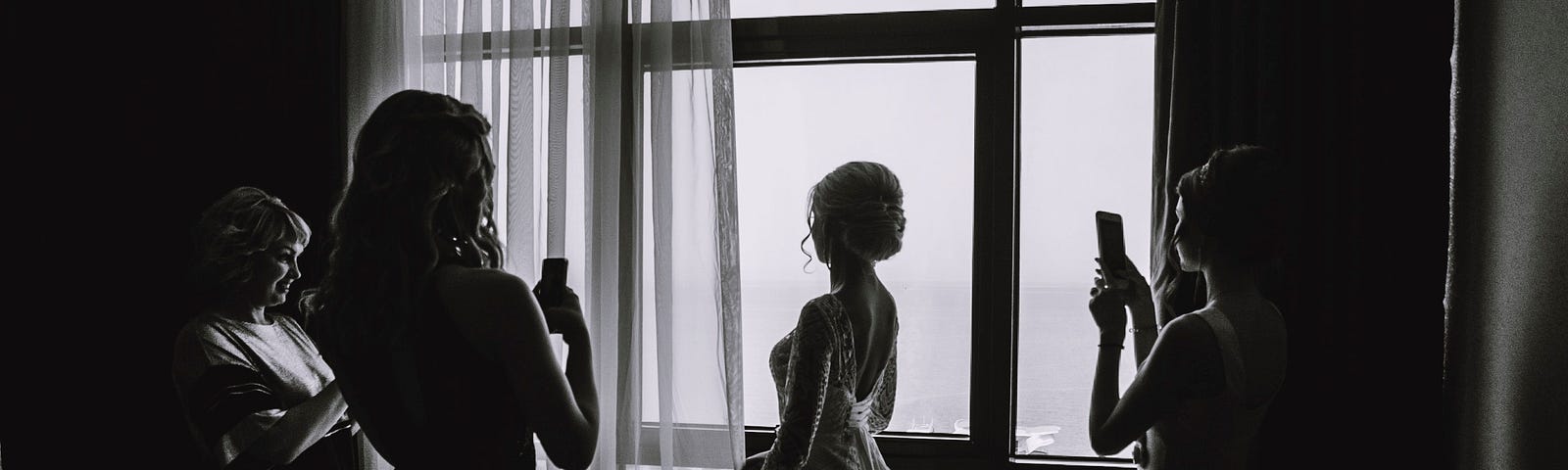 A bride is photographed by her attendants.