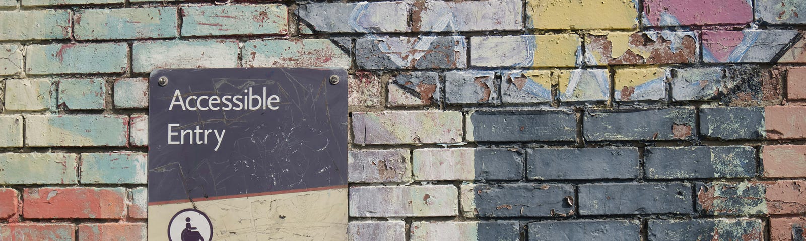 A colourfully painted brick wall has a sign saying ‘Accessible Entry’.