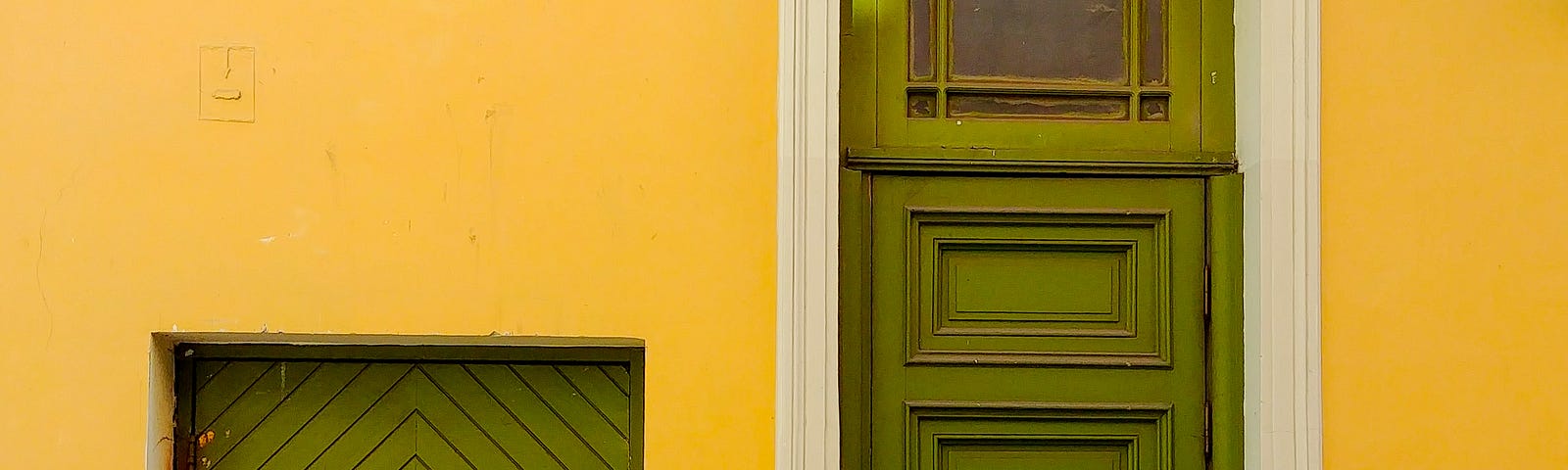 Small vs large green doors against a yellow wall