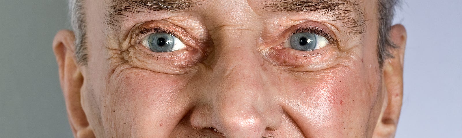 close up of smiling older man with mustache and blue eyes