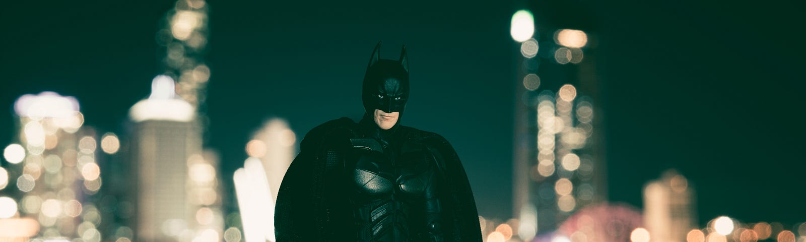 Photo of Batman with night skyline in background.