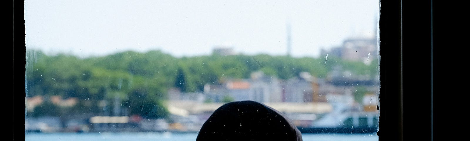 A woman looking out onto the water through a window.