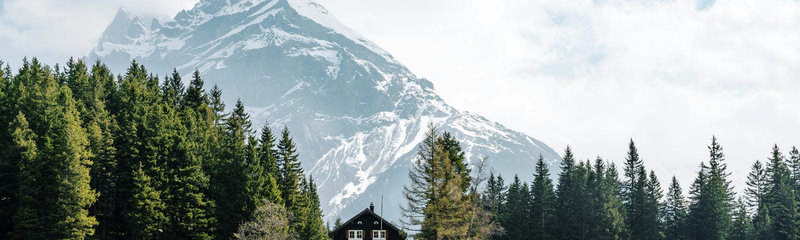 A wooden chalet on a lake in Switzerland. A snowy mountain in the background