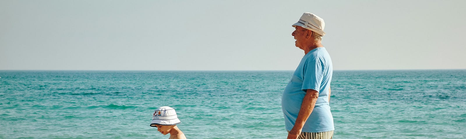 A child and an old man on the beach.