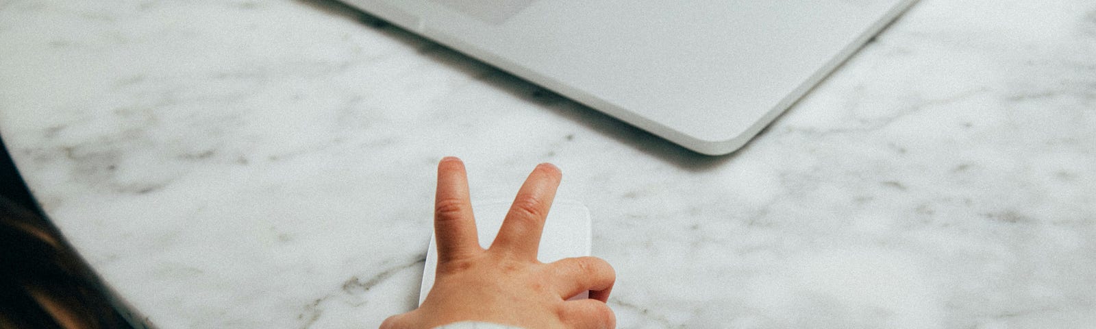 A baby with a computer mouse in his hands, lookng at a laptop.