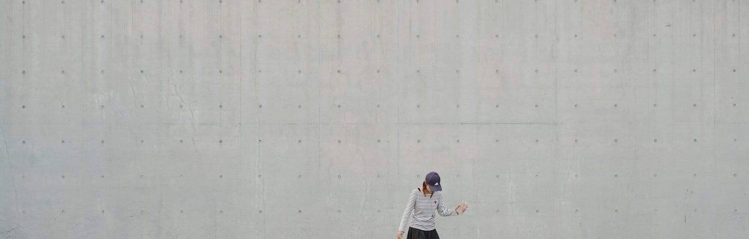 girl skateboarding in front of a white wall