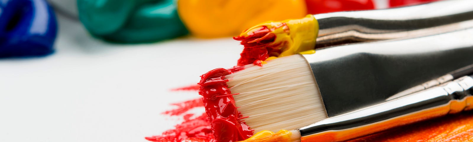 Image of two paintbrushes and several colors of paint.