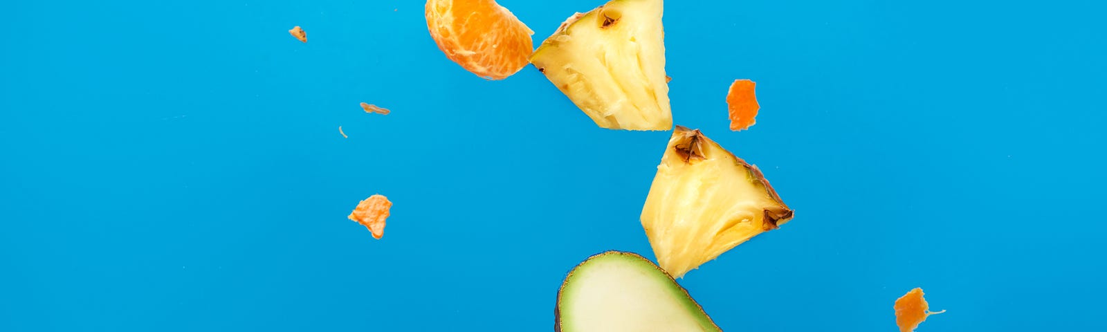 Several cut fruits fly off of a fork. Blue background. Eating a plant-based diet lowers the risk of premature mortality, cardiovascular problems, and cancer.