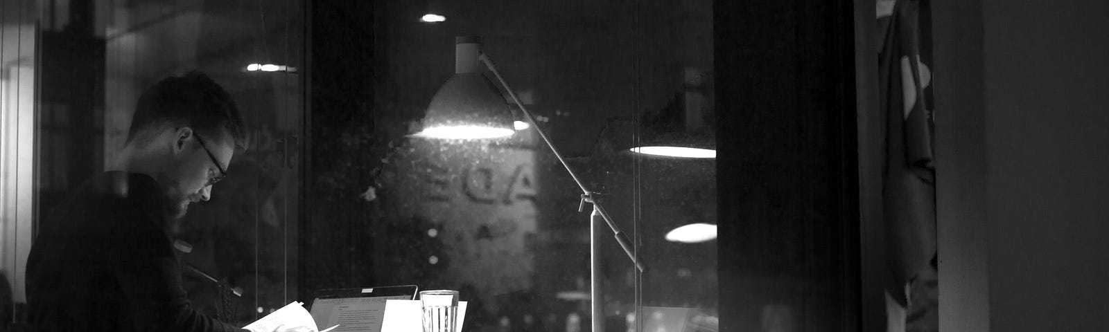 A man reads at night in a cafe