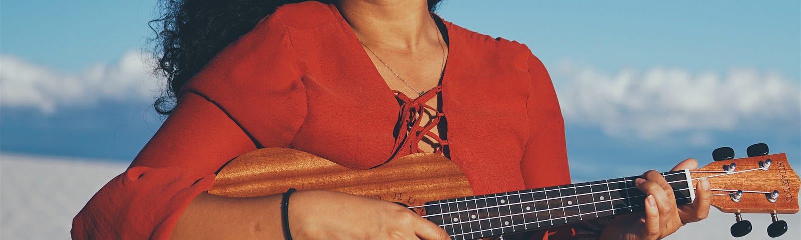 A woman playing the ukulele on a beach.