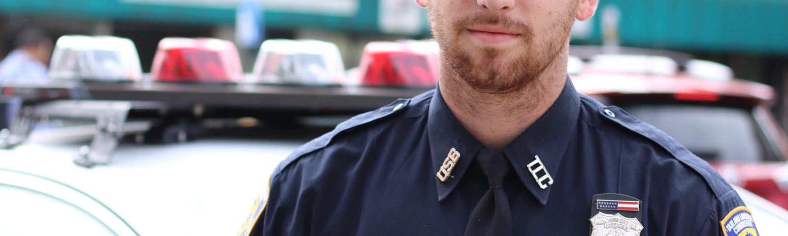 A photo of a police officer in front of his car.