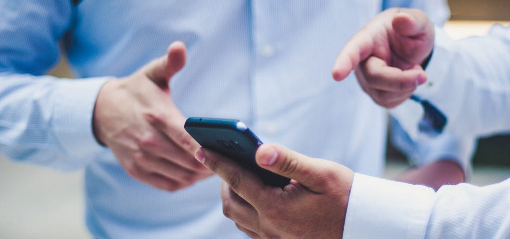 Two men discussing something on a smartphone.