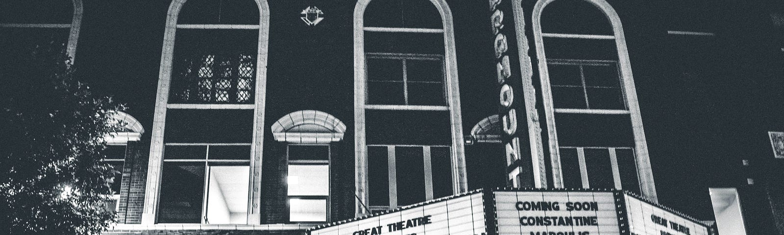 Black and white photo of Paramount theater sign reading “presents Singing in the Rain” with show times.