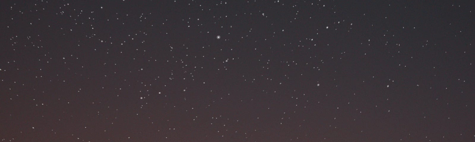 two people hold each other against a quickly darkening night sky — the stars are visible above them