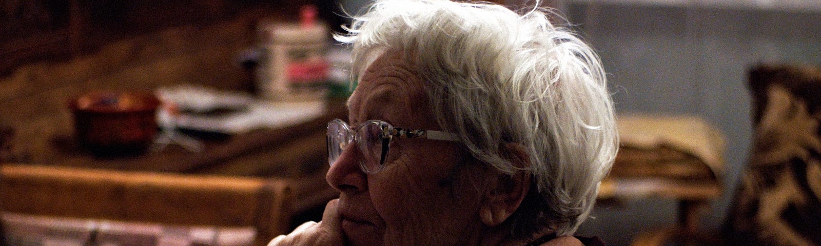 Elder woman with white hair sitting alone at a table