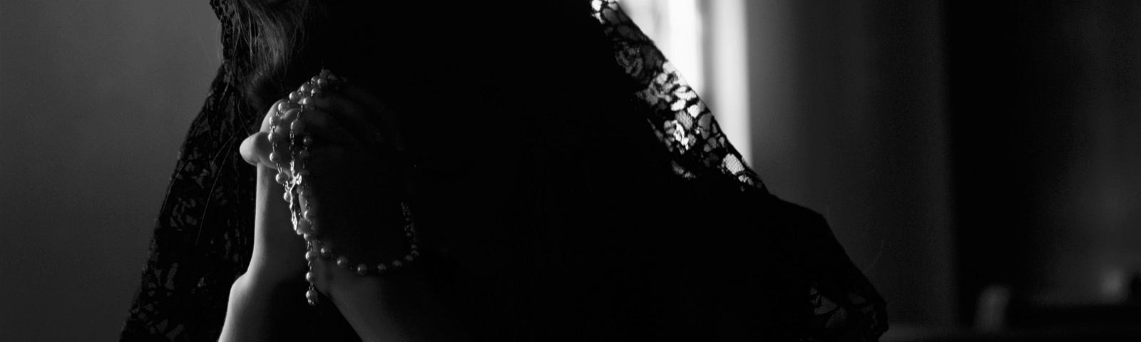 Black and white photo showing a woman in prayer.