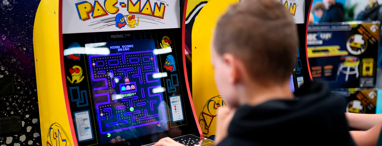 a young boy playing pac man game at an arcade