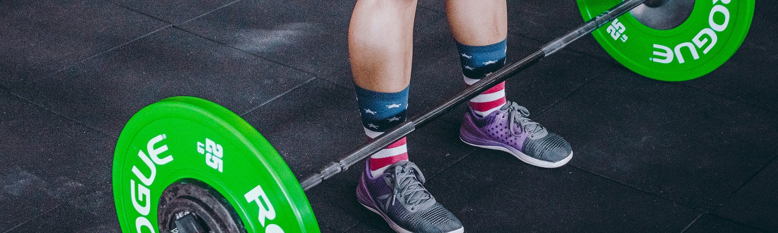 A person stands in fromt of a barbell.