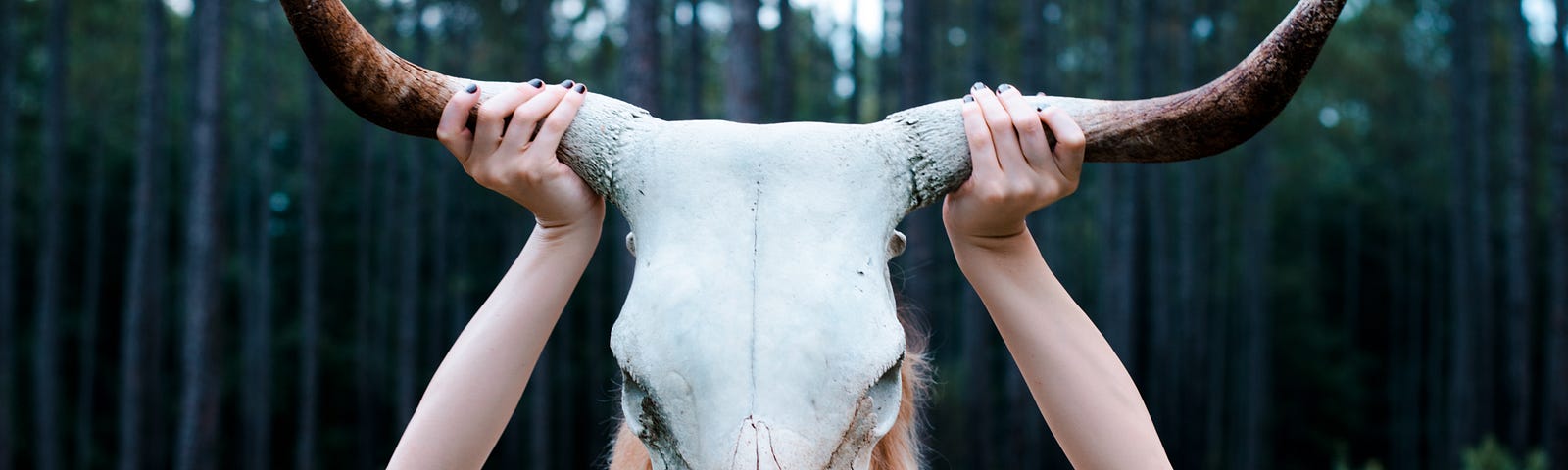 Woman in a white dress holding a ram skull